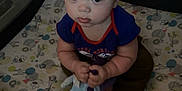 Joey is registered to the contest to win money with this photo: baby, child, playpen, toy, plush_toy, patterned_mattress, animal_print, curious, indoor, sitting, mesh_sides, infant, clothing, short_hair, large_eyes, hands, feet, looking_up, cute, home