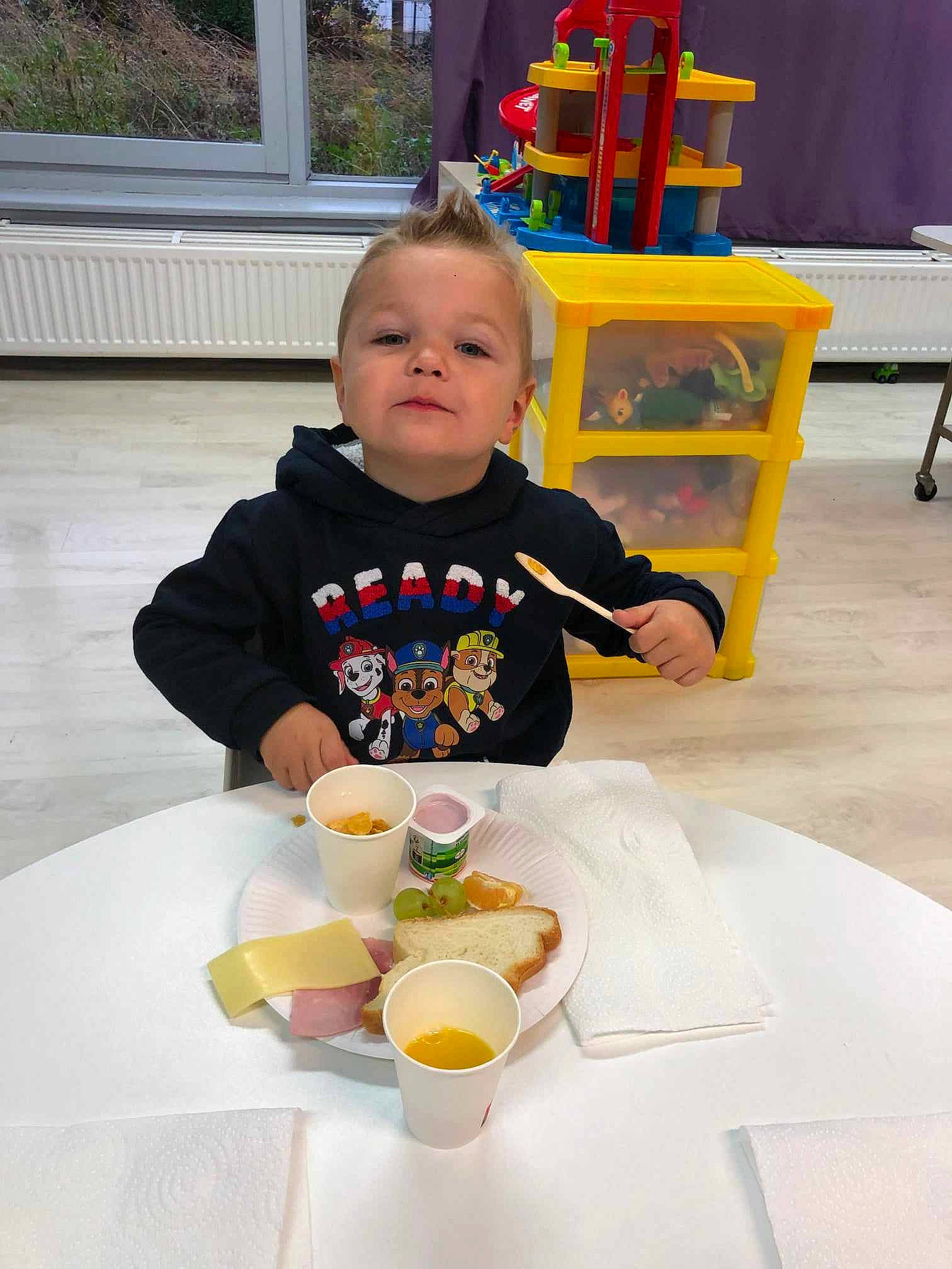 Adham participe au concours pour gagner de l'argent avec cette photo : baby, baby_toddler_clothing, chair, comfort_food, cuisine, cup, dishware, drinkware, eating, event, food, orange, person, plate, serveware, smile, t_shirt, table, tableware, toddler
