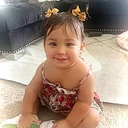 Alana is registered to the contest to win money with this photo: toddler, child, smiling, sitting, indoor, carpet, dress, hair_bows, sneakers, living_room, couch, pillow, cute, happy, person, baby, portrait, floor, young_child, fun