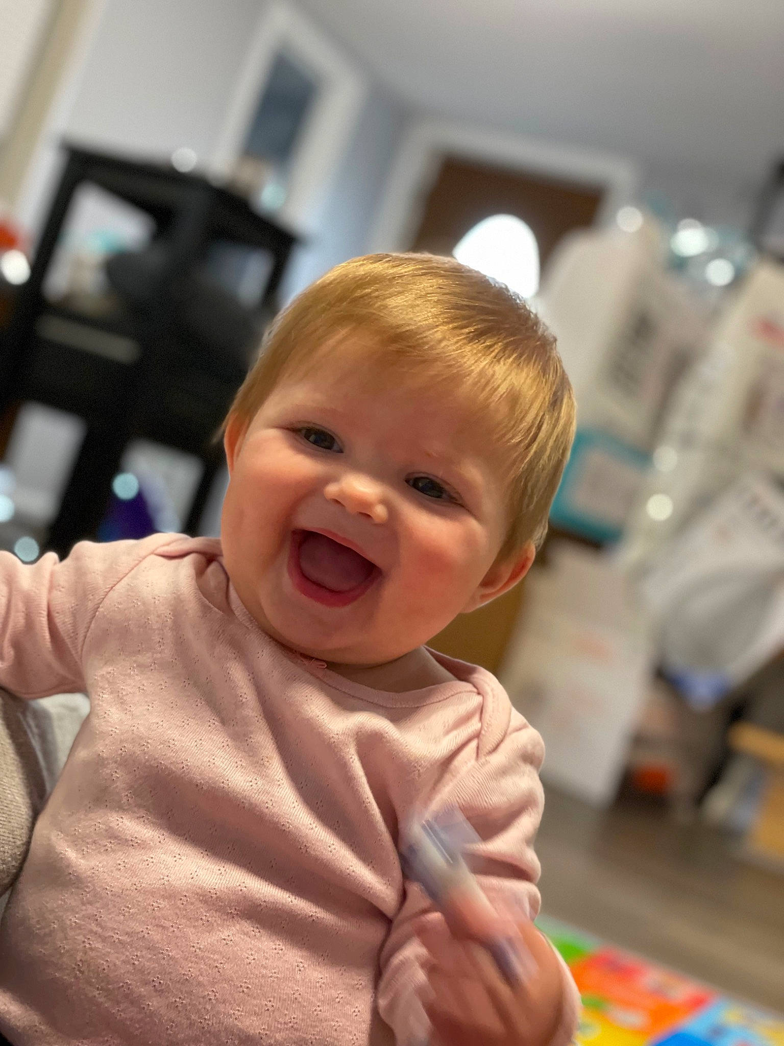 Melanie is registered to the contest to win money with this photo: baby, baby_toddler_clothing, cheek, child, flooring, fun, happy, iris, laugh, nose, person, room, sitting, skin, smile, standing, thumb, toddler, vacation, wood