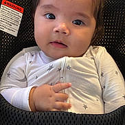 Riley is registered to the contest to win money with this photo: baby, infant, face, eyes, hand, onesie, stars, bouncer, babybjorn, warning_label, clothing, soft_light, portrait, cute, indoor, child, young, person, expression, closeup