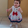 Lady is registered to the contest to win money with this photo: toddler, child, girl, dress, white_shoes, pigtails, smiling, standing, indoors, tile_floor, red_bow, nautical_theme, anchor, boat, cute, happy, person, portrait, young_child, fashion