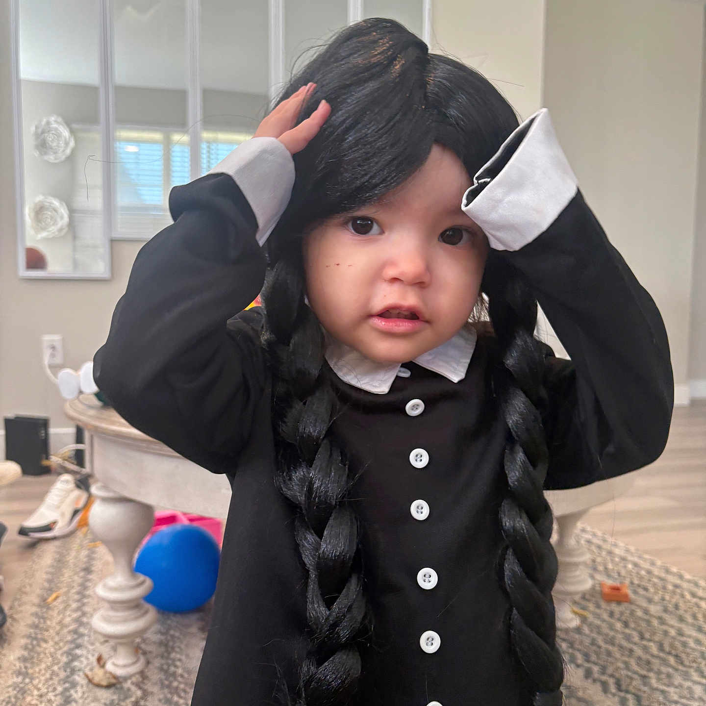 Lady is registered to the contest to win money with this photo: ball, black_clothing, braids, buttons, carpet, child, cute, floor, hands_on_head, indoor, living_room, mirror, person, portrait, shoes, table, toddler, white_collar, wig, window