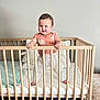 toddler, baby, crib, wooden_crib, standing, smiling, indoor, child, pajamas, blanket, pillow, bed, furniture, person, cute, happy, home, infant, playful, young_child