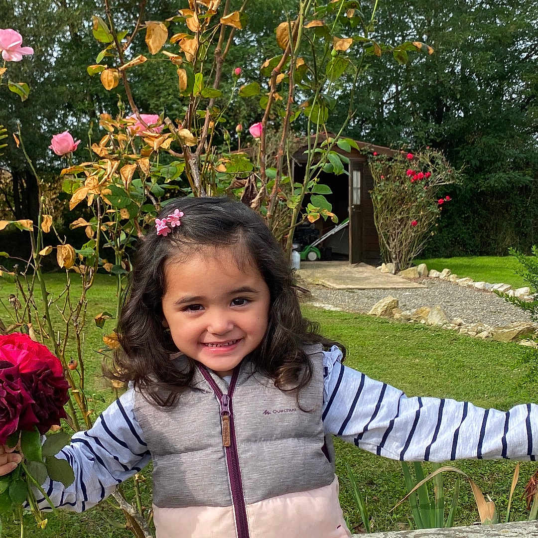 Monychan a rejoint le concours — aidez-le/la à gagner de superbes lots ! child, cute, daytime, flowers, garden, girl, grass, greenery, hair_clip, happy, nature, outdoor, pink, plants, rocks, roses, shed, smiling, striped_clothing, vest