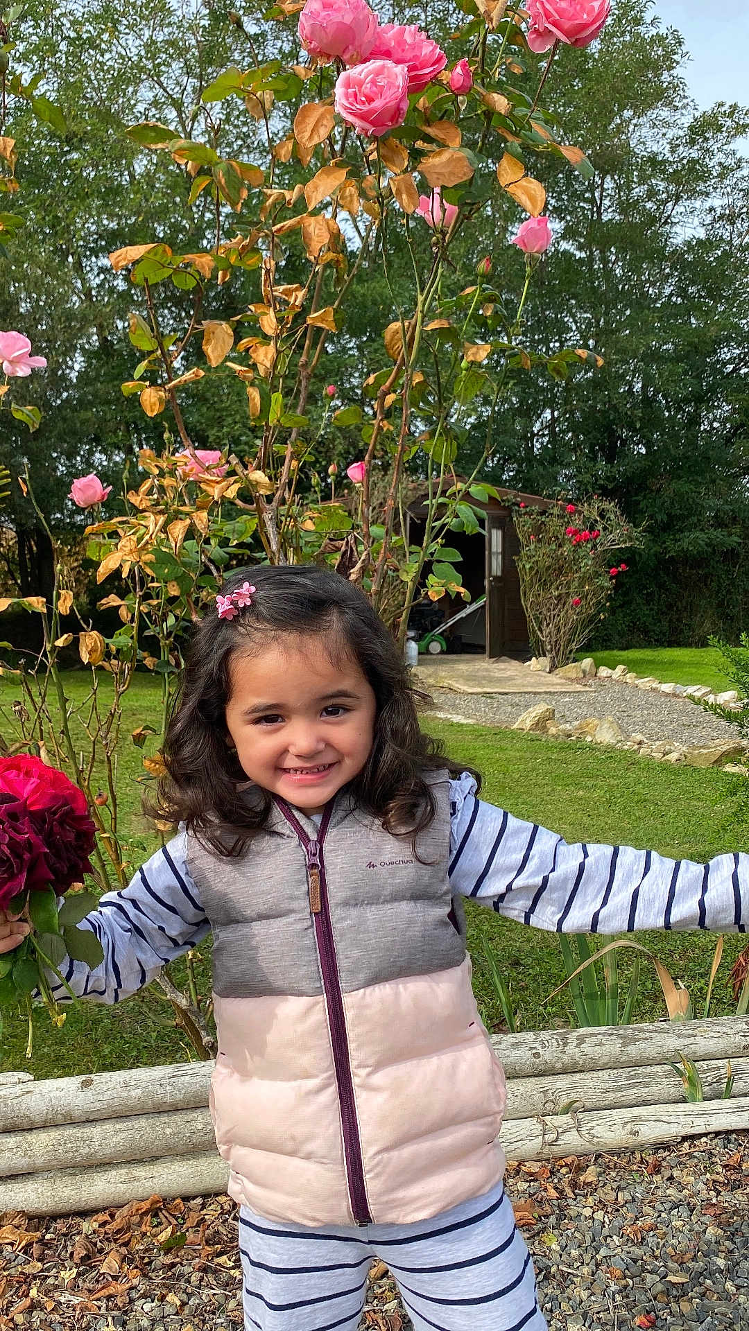 Monychan a rejoint le concours — aidez-le/la à gagner de superbes lots ! child, girl, smiling, roses, flowers, garden, outdoor, greenery, pink, hair_clip, vest, striped_clothing, plants, nature, shed, grass, rocks, happy, cute, daytime