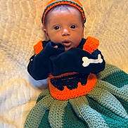 Carolynn joined the competition — help win amazing prizes! baby, infant, knitted_hat, pom_pom, knitted_outfit, blanket, striped_blanket, soft_texture, face, wide_eyes, curious, lying_down, cute, child, newborn, warm_clothing, indoors, portrait, small_hands, cozy