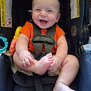 Noah is registered to the contest to win money with this photo: baby, infant, car_seat, orange_shirt, smiling, happy, child, cute, straps, seatbelt, foot, hands, sitting, indoors, young_child, joyful, playful, person, portrait, baby_toys