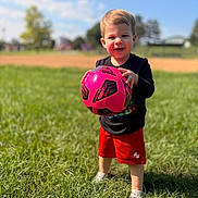 Wesley joined the competition — help win amazing prizes! child, toddler, boy, soccer, football, soccer_ball, pink_ball, outdoor, sports_field, grass, sunny, blue_sky, smiling, portrait, standing, shorts, black_shirt, shoes, playground, baseball_field