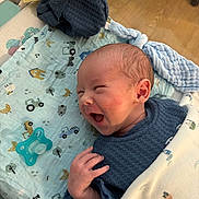 Mason joined the competition — help win amazing prizes! baby, newborn, infant, smiling, yawning, blue_clothing, blanket, pacifier, patterned_cloth, hand, face, head, skin, indoors, floor, wooden_floor, sleepwear, cute, cozy, happy