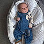 Mason is registered to the contest to win money with this photo: baby, infant, denim_overalls, elephant_pattern, baby_nest, cushion, carpet, blue_shoes, clothing, child, portrait, indoor, cute, young_child, baby_boy, footwear, fabric, resting, looking, person