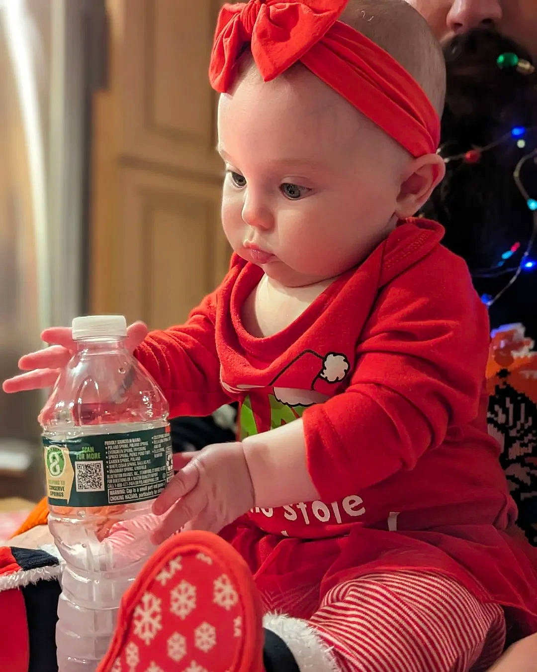 Francesca is registered to the contest to win money with this photo: baby, baby_toddler_clothing, bottle, cap, child, christmas, christmas_eve, drink, drinkware, event, fun, happy, hat, holiday, person, plastic_bottle, red, sitting, standing, toddler