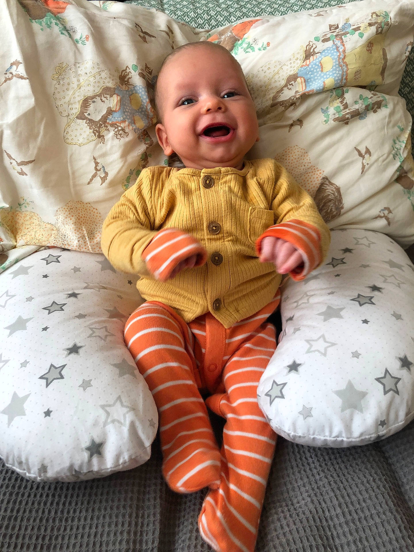 baby, bed, clothing, couch, cushion, face, furniture, glove, happy, head, homedecor, knitwear, pants, person, photography, pillow, portrait, sitting, smile, sweater