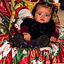 baby, child, face, portrait, holiday, christmas, festive, blanket, pillow, santa_claus, clothing, glitter, chair, indoor, cute, expression, holiday_decor, red, green, cozy
