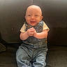 baby, child, smiling, denim_overalls, sitting, couch, happy, infant, clothing, hands, face, portrait, indoor, cute, young, person, feet, footwear, light, texture