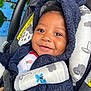 Braylin is registered to the contest to win money with this photo: baby, infant, smiling, car_seat, stroller, hooded_jacket, cozy, closeup, face, eyes, cheeks, portrait, buckle, fabric, pattern, safety_label, mural, blue_wall, cute, happy