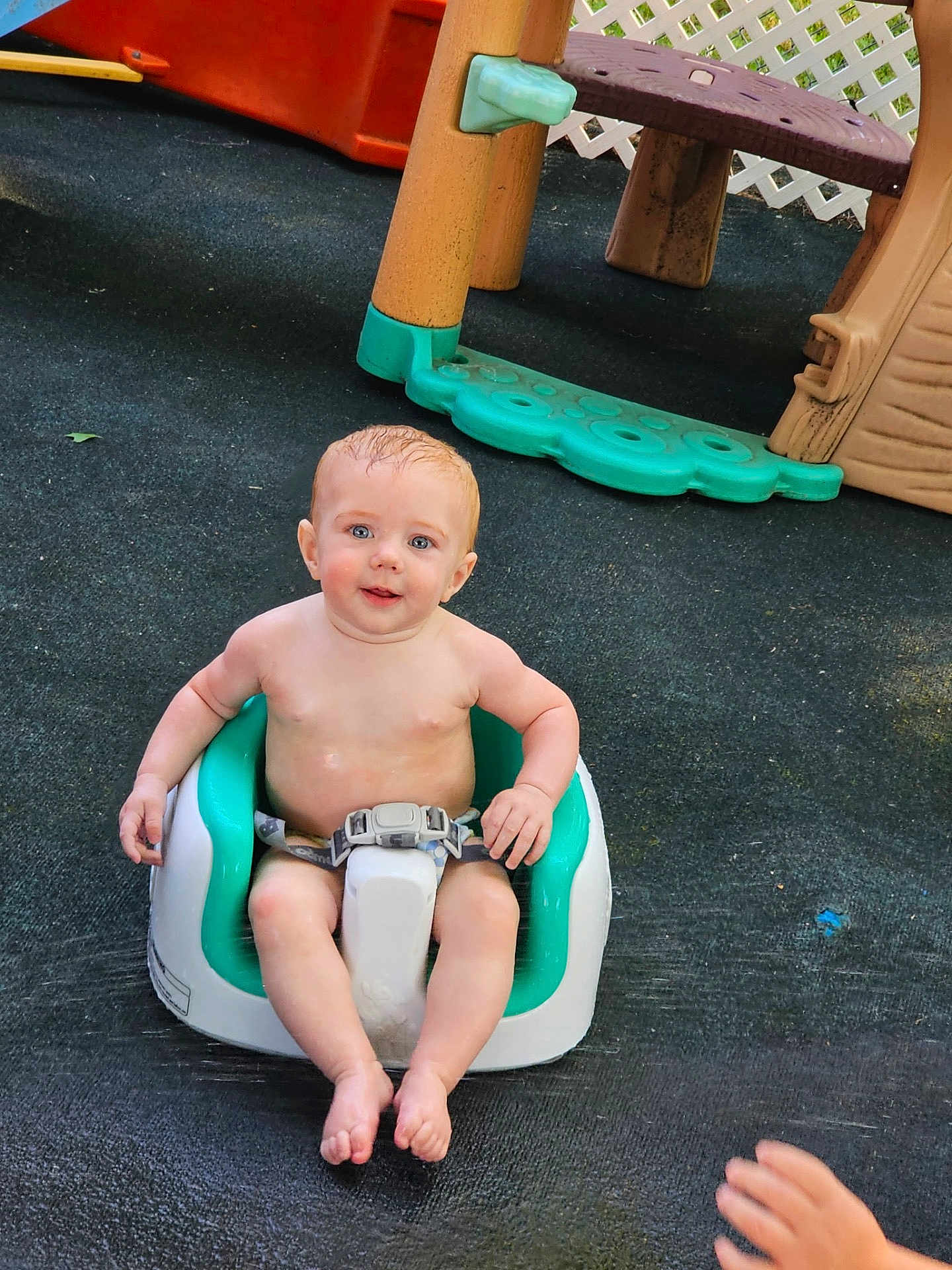 Owen is registered to the contest to win money with this photo: baby, child, seat, outdoor, playground, toy, smiling, happy, skin, bare_chest, hand, play_area, plastic, fence, foot, young_child, person, infant, sitting, daylight