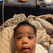 Truce is registered to the contest to win money with this photo: baby, infant, face, eyes, blanket, clothing, curly_hair, indoor, soft_toys, bottle, closeup, expression, child, cute, person, portrait, cozy, home, resting, young