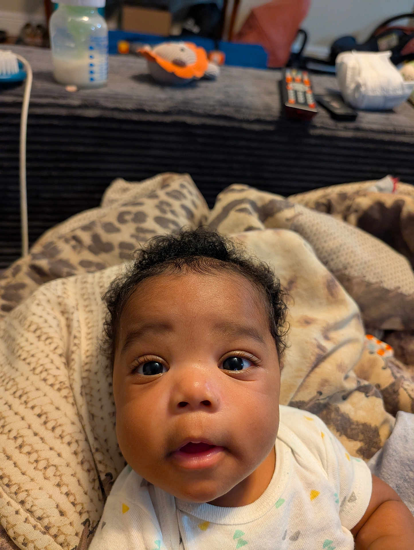 Truce is registered to the contest to win money with this photo: baby, infant, face, eyes, blanket, clothing, curly_hair, indoor, soft_toys, bottle, closeup, expression, child, cute, person, portrait, cozy, home, resting, young