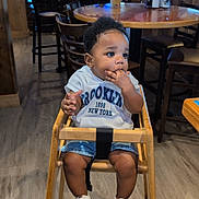 Truce is registered to the contest to win money with this photo: american_flag, baby, casual_clothing, chairs, child, curly_hair, cute, flooring, high_chair, indoor, menu, people_in_background, restaurant, sneakers, table, television, toddler, waiting, wooden_chair, wooden_furniture