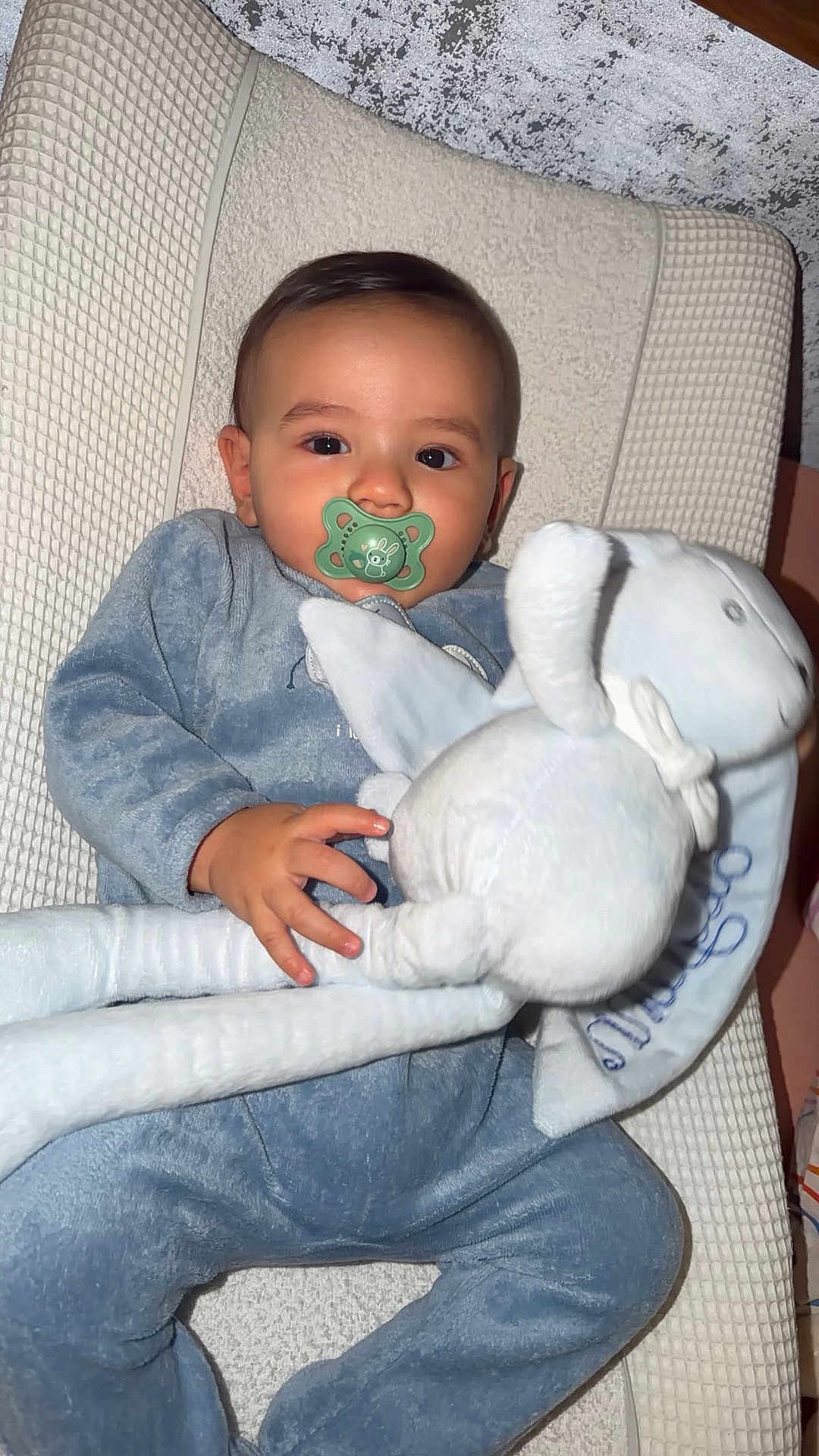 Leyann a rejoint le concours — aidez-le/la à gagner de superbes lots ! baby, child, pacifier, plush_toy, stuffed_animal, blue_onesie, cushion, indoor, infant, cute, lying_down, hand, face, head, soft_toy, comfort, relaxed, young_child, home, cozy
