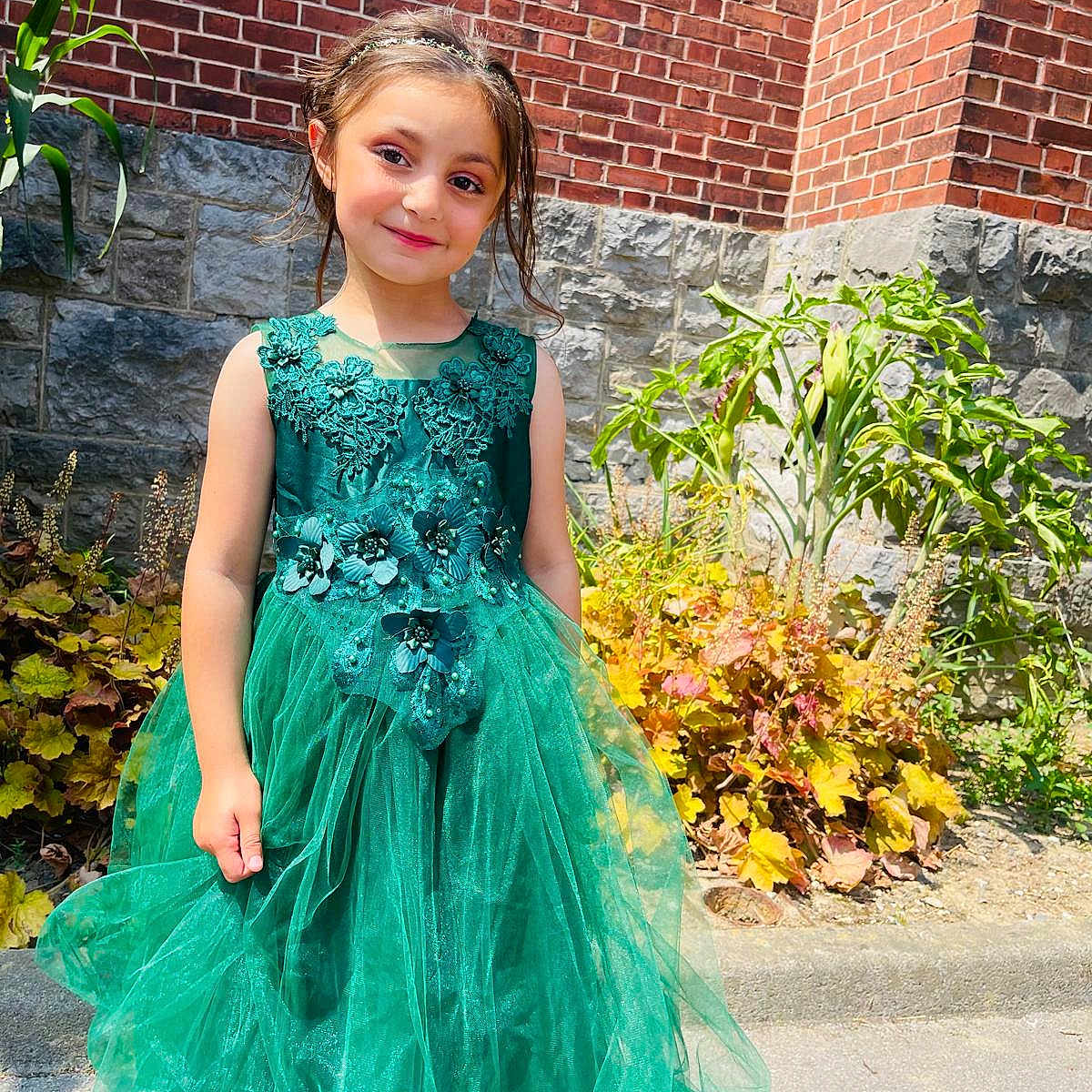 Hiba participe au concours pour gagner de l'argent avec cette photo : brick_wall, child, cute, daylight, dress, fashion, flower_headband, garden, girl, green_dress, happy, nature, outdoor, plants, portrait, sidewalk, smile, stone_wall, sunlight, young
