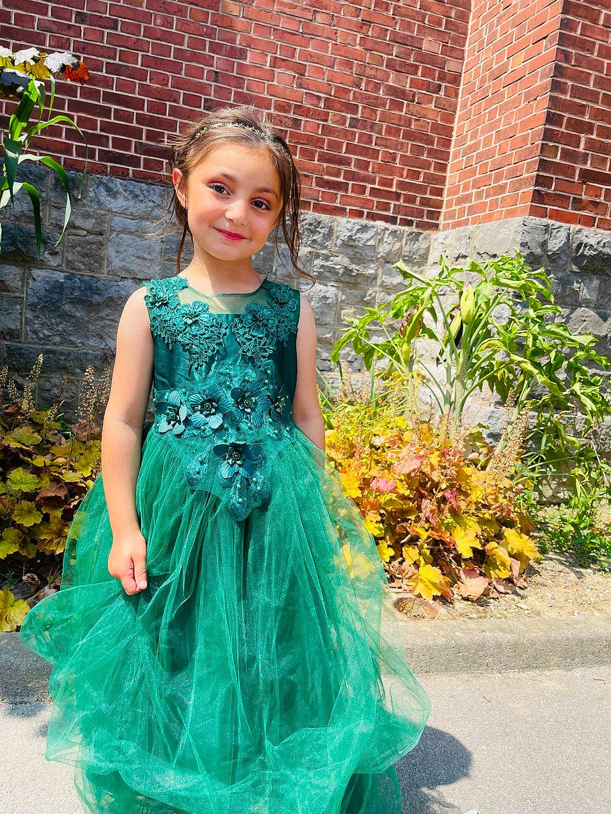 Hiba participe au concours pour gagner de l'argent avec cette photo : brick_wall, child, cute, daylight, dress, fashion, flower_headband, garden, girl, green_dress, happy, nature, outdoor, plants, portrait, sidewalk, smile, stone_wall, sunlight, young