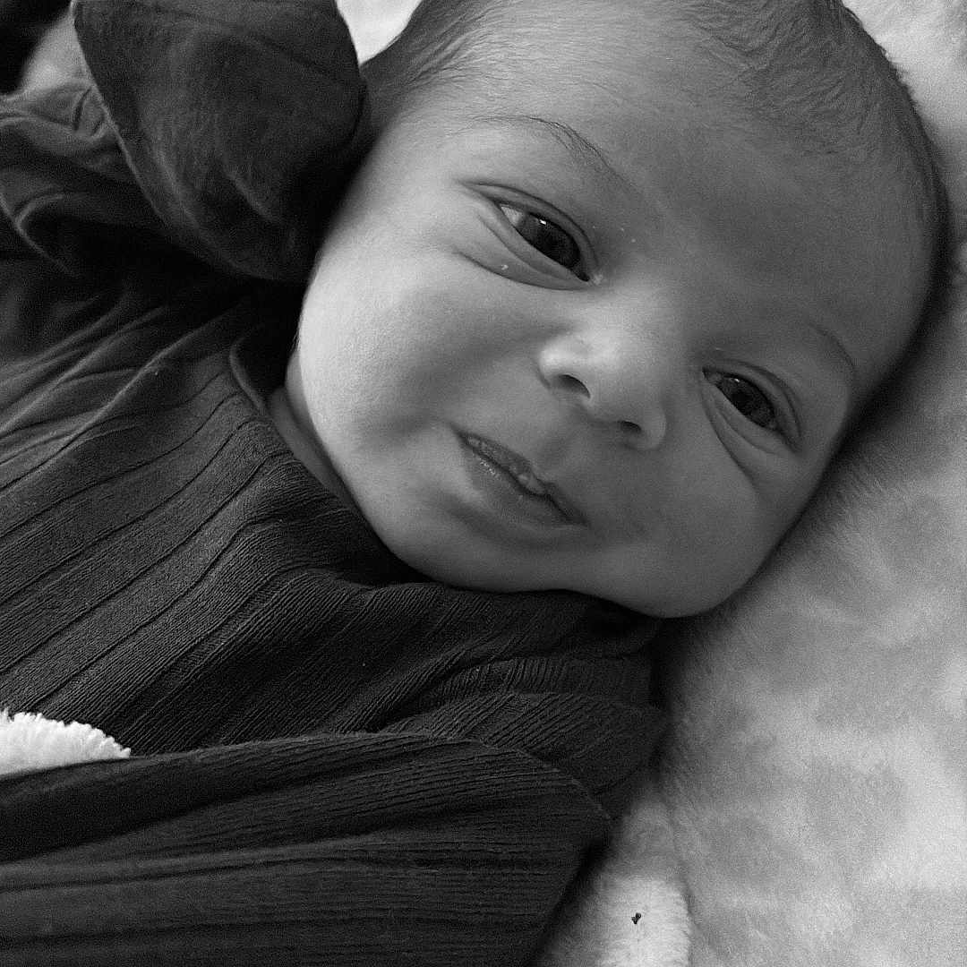 Zacheriah is registered to the contest to win money with this photo: baby, babywear, black_and_white, blanket, child, closeup, clothing, cute, expression, face, head, infant, lying_down, newborn, person, portrait, skin, sleepwear, soft, texture