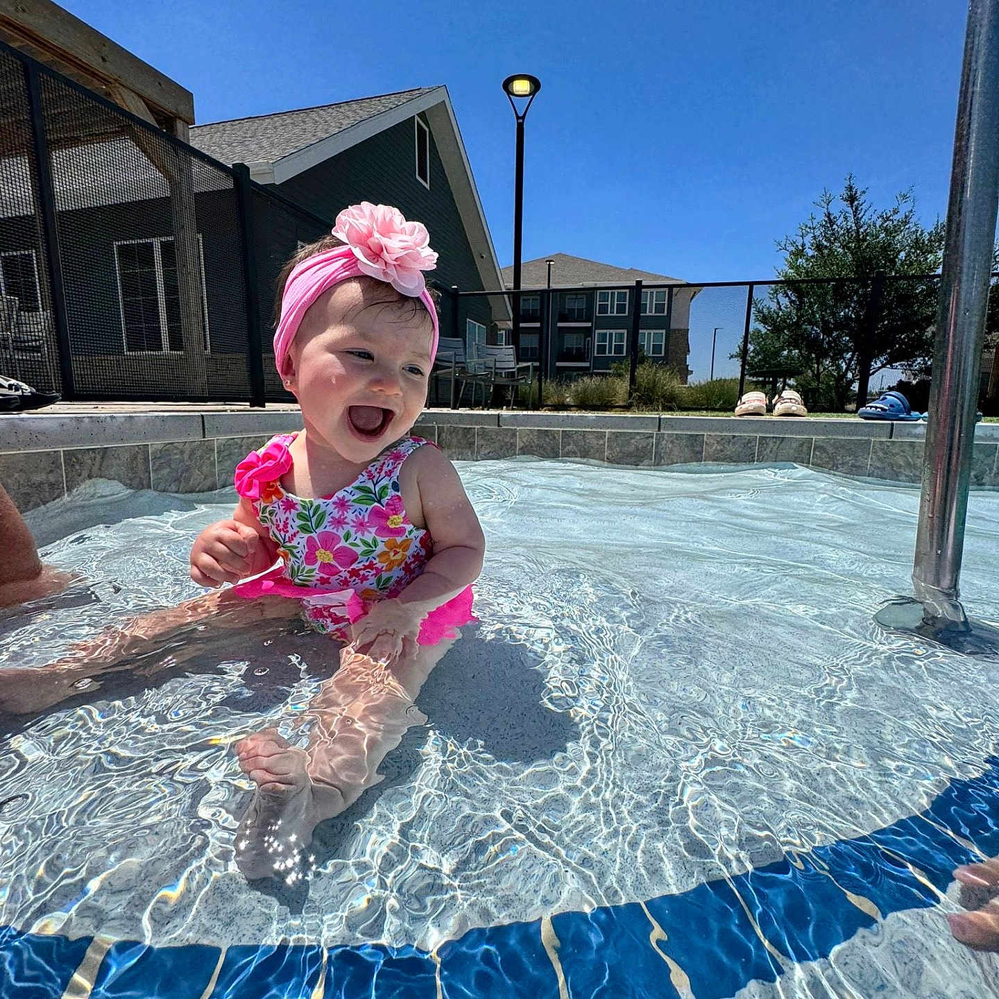 Roseily is registered to the contest to win money with this photo: baby, blue_sky, child, fence, flower, foot, happy, headband, outdoor, person, play, pool, residential, smiling, splashing, summer, sunny, swimsuit, water, water_reflection