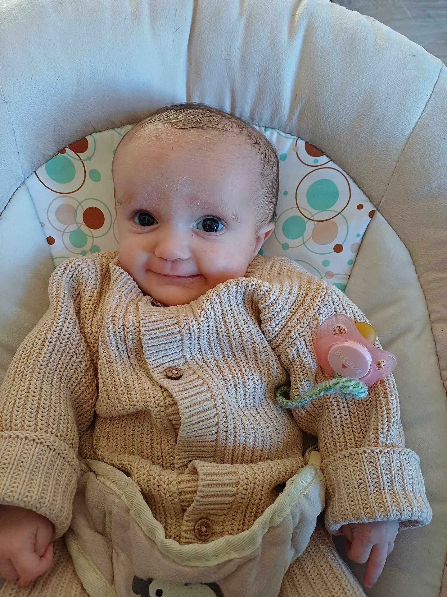 Lorianna a rejoint le concours — aidez-le/la à gagner de superbes lots ! baby, infant, smile, knit_cardigan, pacifier, pacifier_clip, baby_seat, cushion, patterned_insert, circles, hand, eyes, indoor, cozy, fabric, portrait, cute, tiny_fingers, wood_floor, soft_lighting
