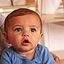 baby, blue_clothing, child, closeup, curious, cute, expression, eyes, face, hair, head, human, indoor, infant, mouth_open, person, portrait, seated, skin, young