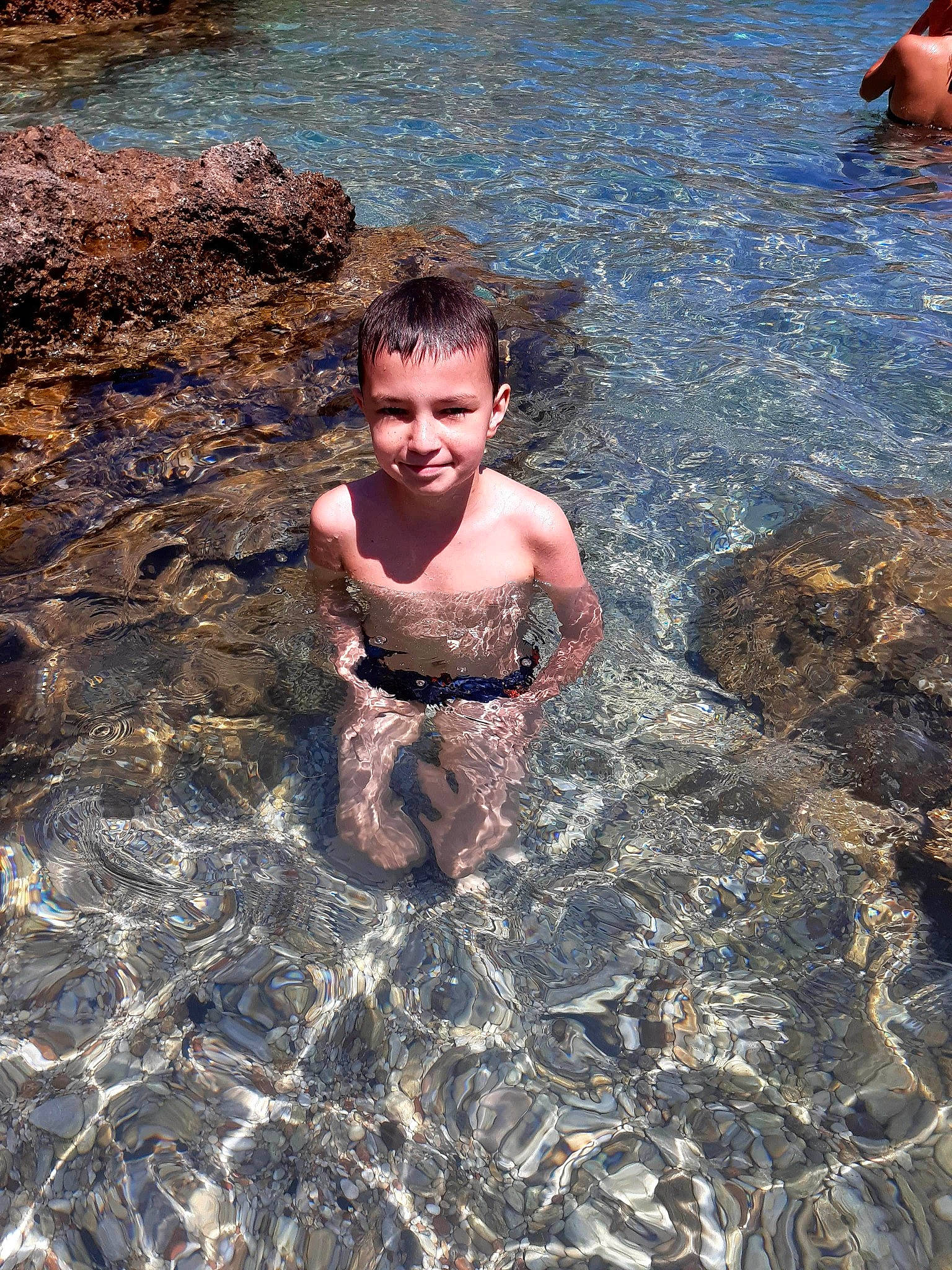 Noah participe au concours pour gagner de l'argent avec cette photo : barechested, bathing, chest, child, fun, happy, joy, lake, leisure, ocean, outdoor_recreation, people_on_beach, person, personal_protective_equipment, play, recreation, rock, smile, swimmer, swimwear