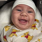 Dior is registered to the contest to win money with this photo: baby, smiling, infant, white_cap, winnie_the_pooh, onesie, cute, happy, face, child, portrait, closeup, cushion, indoor, soft_lighting, baby_clothes, young_child, expression, headwear, comfort