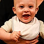 Huxley is registered to the contest to win money with this photo: adult, baby, bib, child, closeup, clothing, cute, expression, face, hand, happy, holding, indoor, infant, person, portrait, skin, smiling, sweater, watch