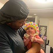 Jazzlyn joined the competition — help win amazing prizes! adult, affection, baby, baby_hat, bonnet, casual_wear, child, colorful_clothing, curious, facial_expression, family, holding, home_interior, indoor, love, man, person, portrait, smile, tattoo