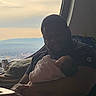 Jazzlyn is registered to the contest to win money with this photo: baby, blanket, caring, cityscape, clouds, comfort, family, gentle, holding, indoor, love, mountains, peaceful, person, portrait, relaxation, seated, sky, soft, window