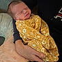 adult, baby, blanket, comfort, couch, cozy, cradling, fabric, floral_pattern, hand, indoor, infant, newborn, peaceful, pillow, portrait, sleeping, smiling, wrapped, yellow
