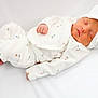 newborn, baby, sleeping, pajamas, white_clothing, headband, bow, floral_pattern, infant, resting, soft_texture, cozy, blanket, cute, peaceful, child, portrait, indoors, small_hands, small_feet