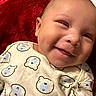 baby, bear_pattern, child, clothing, cozy, cute, expression, face, happy, head, indoors, infant, lying_down, onesie, portrait, red_blanket, skin, smile, soft_texture, young_child