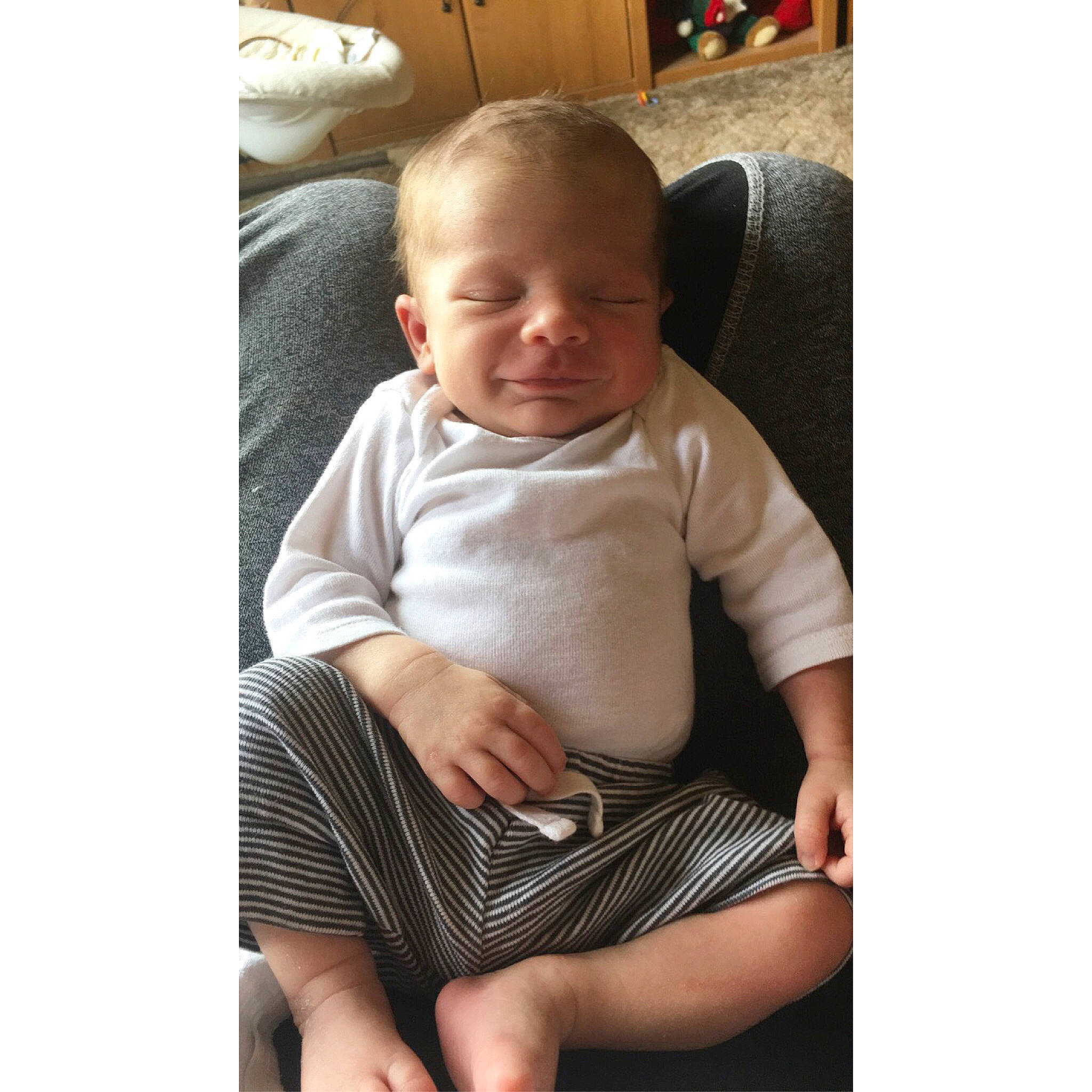 Jacoby is registered to the contest to win money with this photo: arm, baby, baby_products, baby_toddler_clothing, chair, cheek, child, comfort, facial_expression, furniture, head, leg, person, product, sitting, sleeve, smile, t_shirt, toddler