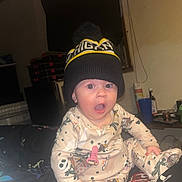 Kaylanna joined the competition — help win amazing prizes! baby, infant, child, portrait, sitting, surprised, wide_eyed, open_mouth, beanie, pom_pom_hat, pajamas, patterned_clothing, indoor, home, flash_photography, furniture, cup, blanket, cozy, family_photo