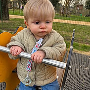 Martin a rejoint le concours — aidez-le/la à gagner de superbes lots ! baby, child, cute, daylight, expression, fence, grass, jacket, jeans, metal_bar, outdoor, pacifier, park, person, play_equipment, playground, shoes, sunset, toddler, trees