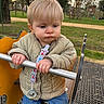 baby, child, cute, daylight, expression, fence, grass, jacket, jeans, metal_bar, outdoor, pacifier, park, person, play_equipment, playground, shoes, sunset, toddler, trees