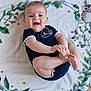 baby, smiling, onesie, blanket, leaf_pattern, owl_pattern, infant, playful, happy, child, cute, skin, feet, hands, head, face, sitting, laying, indoors, portrait