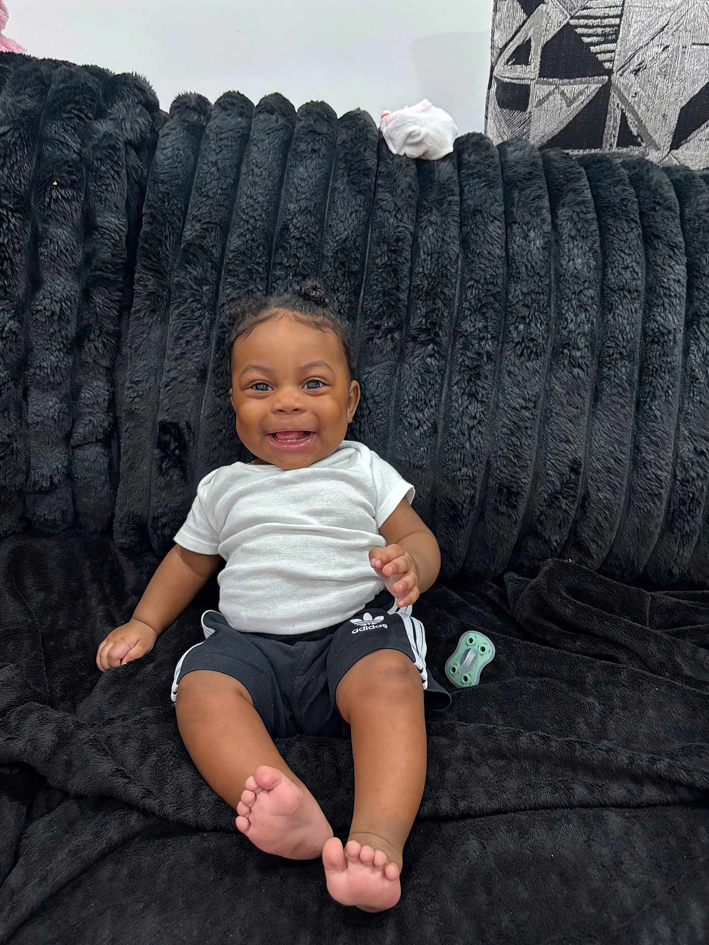 Kaycen joined the competition — help win amazing prizes! baby, child, smiling, sitting, indoor, couch, black_couch, white_shirt, black_shorts, adidas, pacifier, barefoot, happy, cute, portrait, infant, furniture, plush, person, home
