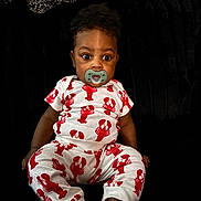 Kaycen is registered to the contest to win money with this photo: baby, child, pacifier, lobster_pattern, white_clothing, red_print, sitting, plush_background, cute, infant, foot, hand, wide_eyes, indoors, portrait, comfort, young_child, clothing_pattern, expression, relaxed