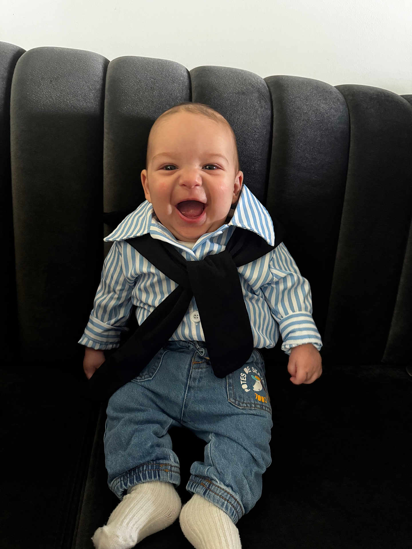 ümit participe au concours pour gagner de l'argent avec cette photo : baby, child, smiling, happy, striped_shirt, jeans, socks, couch, indoor, cute, portrait, seated, clothing, young_child, infant, person, face, expression, joy, casual