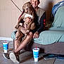 Miklo is registered to the contest to win money with this photo: man, dog, tattoo, smile, couch, floor, tile_floor, drink_cup, casual, indoor, clothing, book, furniture, pet, human, holding, seated, brown_dog, white_marking, relaxed
