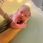 Ezio participe au concours pour gagner de l'argent avec cette photo : baby, infant, bath, water, hands, string_lights, tub, skin, face, person, newborn, arm, wet, soothing, comfort, indoor, lighting, closeup, parent, care