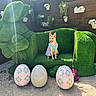 Peaches is registered to the contest to win money with this photo: dog, grass_couch, bunny_shaped_couch, easter_eggs, decorative_eggs, flower_pots, wooden_fence, outdoor, sunlight, pet, animal, costume, leash, spring, garden, playful, cute, greenery, sitting, festive
